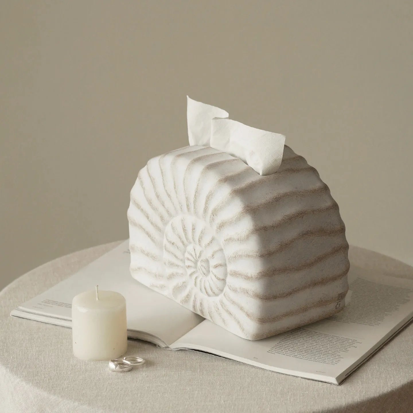 Solid resin conch-shaped tissue box cover in a natural colour on a table.