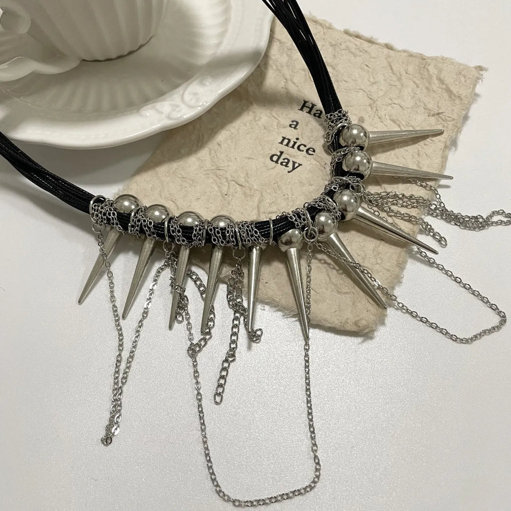 Close-up of a leather necklace with round beads, a winding tassel, and silver rivet details on a dark background.