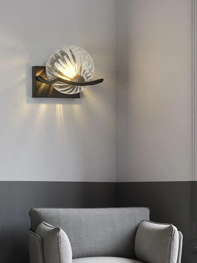 Modern minimalist black wall lamp with striped clear cover mounted beside a bed