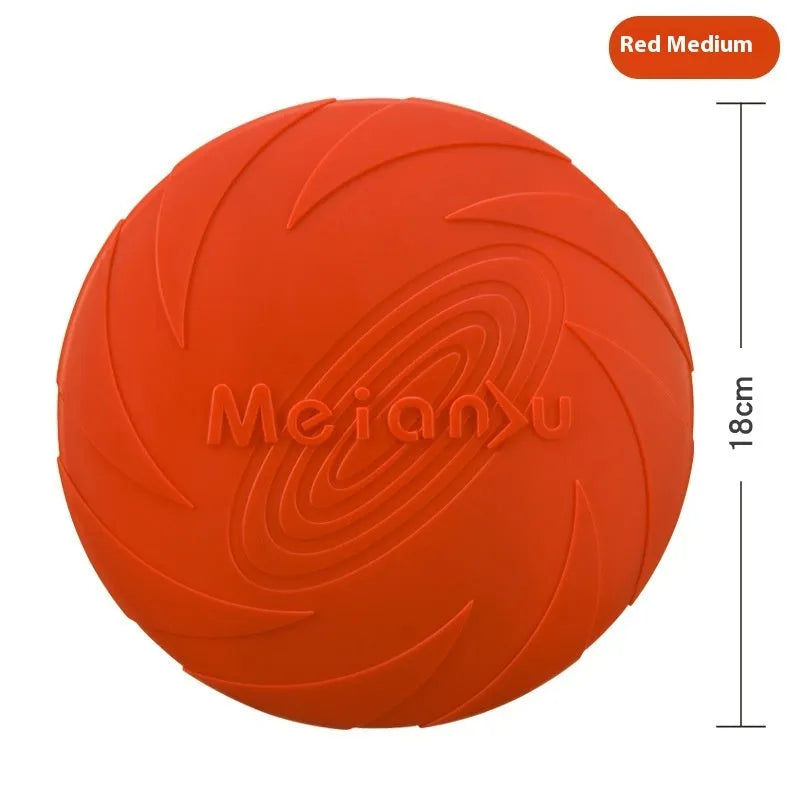 Soft rubber dog frisbee toy in blue, shown on grass for scale.