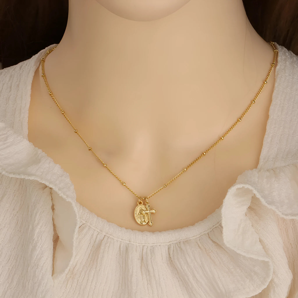 Gold Virgin Mary cross necklace with simple geometric pendant on a chain.