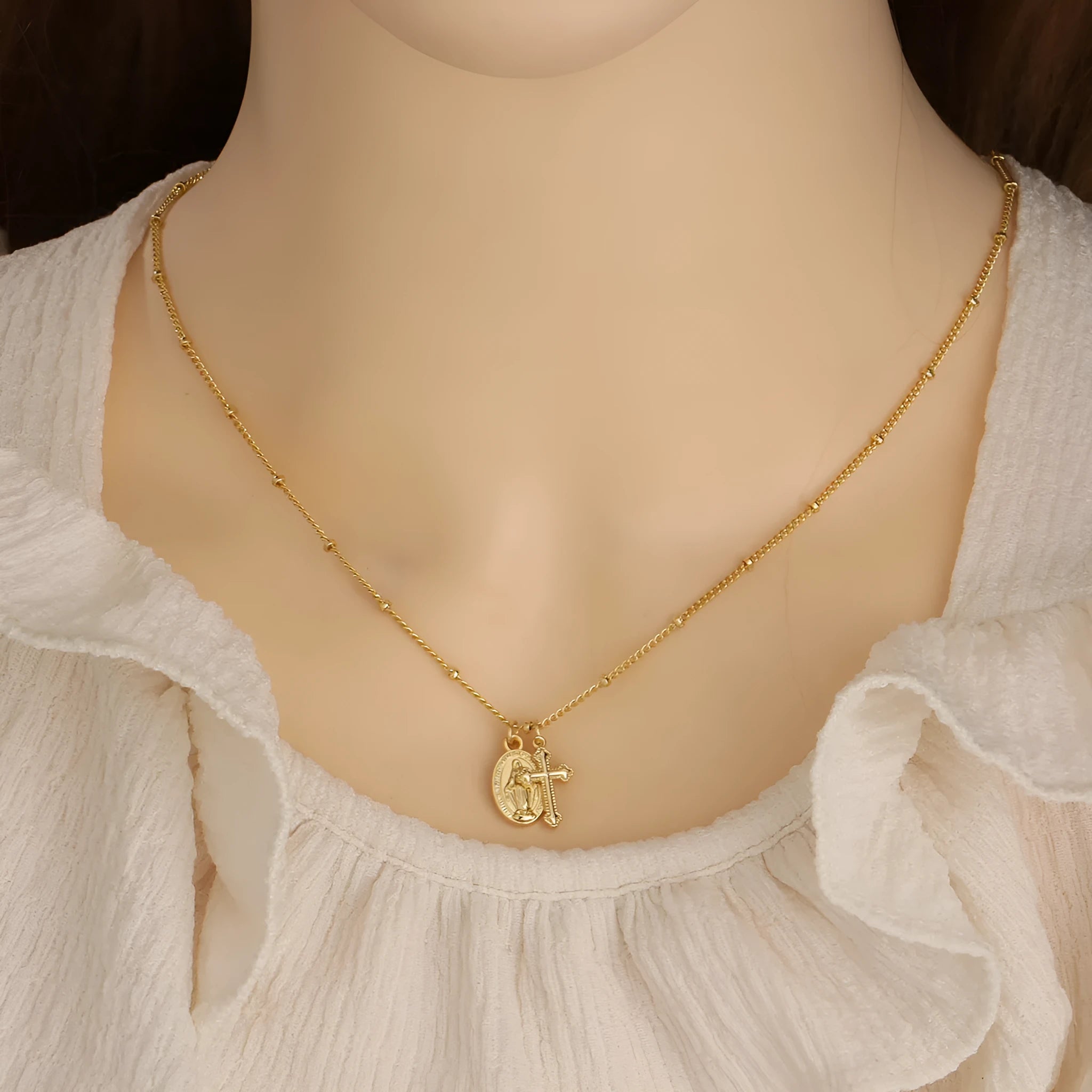 Gold Virgin Mary cross necklace with simple geometric pendant on a chain.