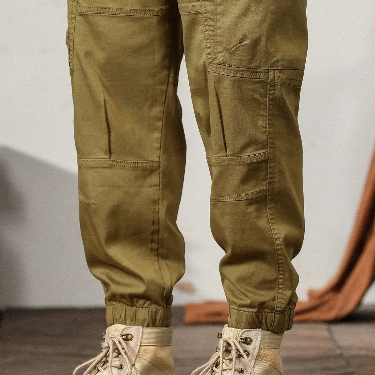 Men's khaki cotton tapered harem pants with ankle bands and a zip fly, laid flat.