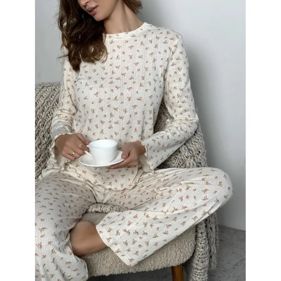 White women's floral print two-piece suit with bell sleeve top and wide leg pants on a hanger.