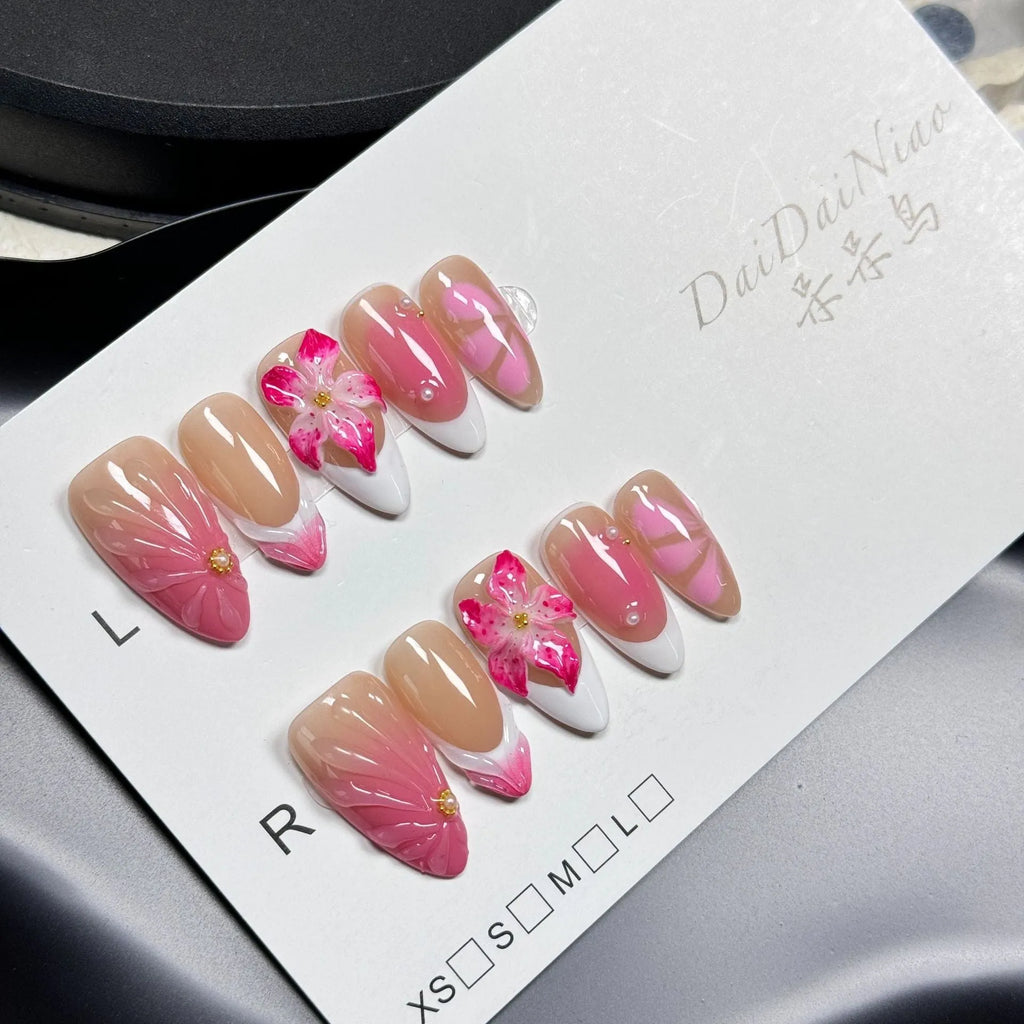 Set of French style artificial nails with white tips and 3D white lily flowers on almond-shaped plastic nail tips.