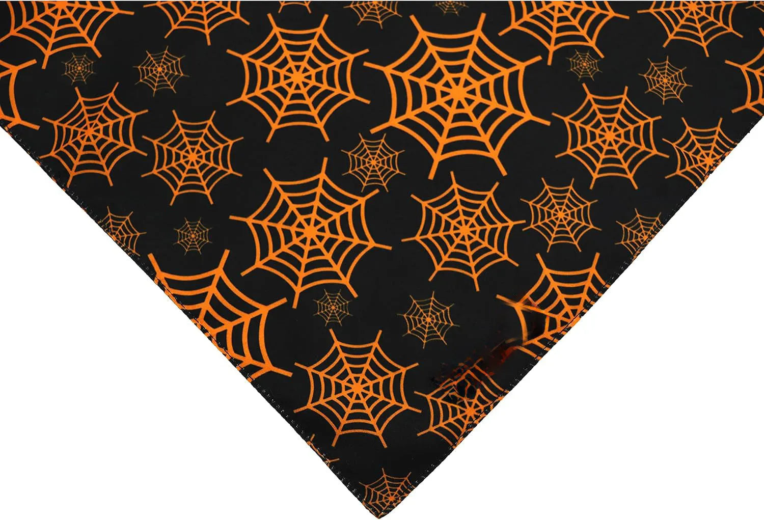 Black and orange reversible Halloween dog bandana with pumpkin and spider web patterns laid flat.