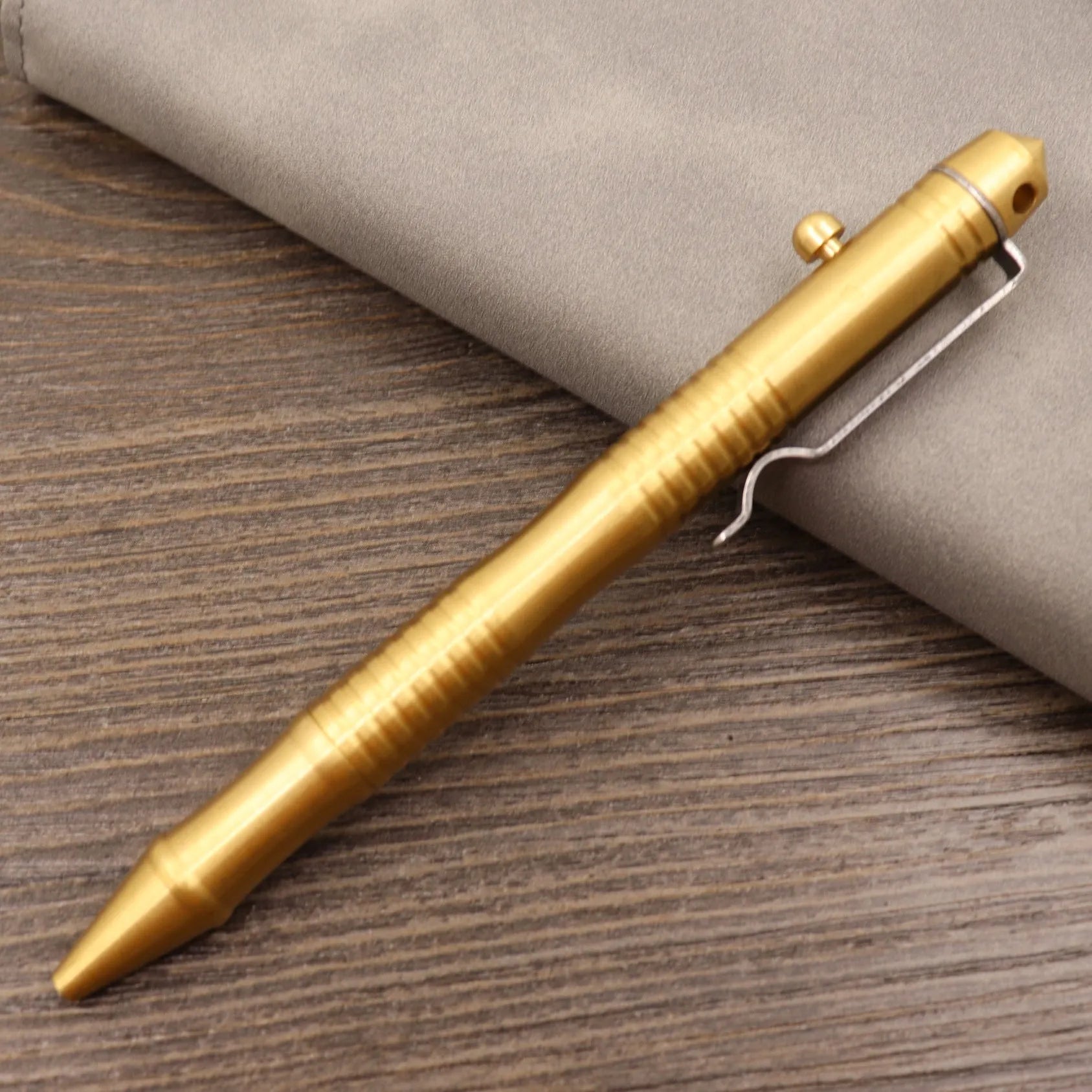Brass bolt-action tactical pen in a retro copper finish, showing press mechanism and textured barrel.