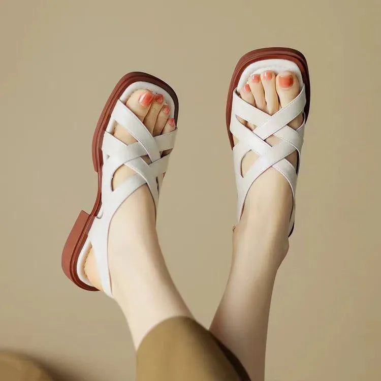 Women's glossy patent leather square toe sandals with cross strap on a brown background
