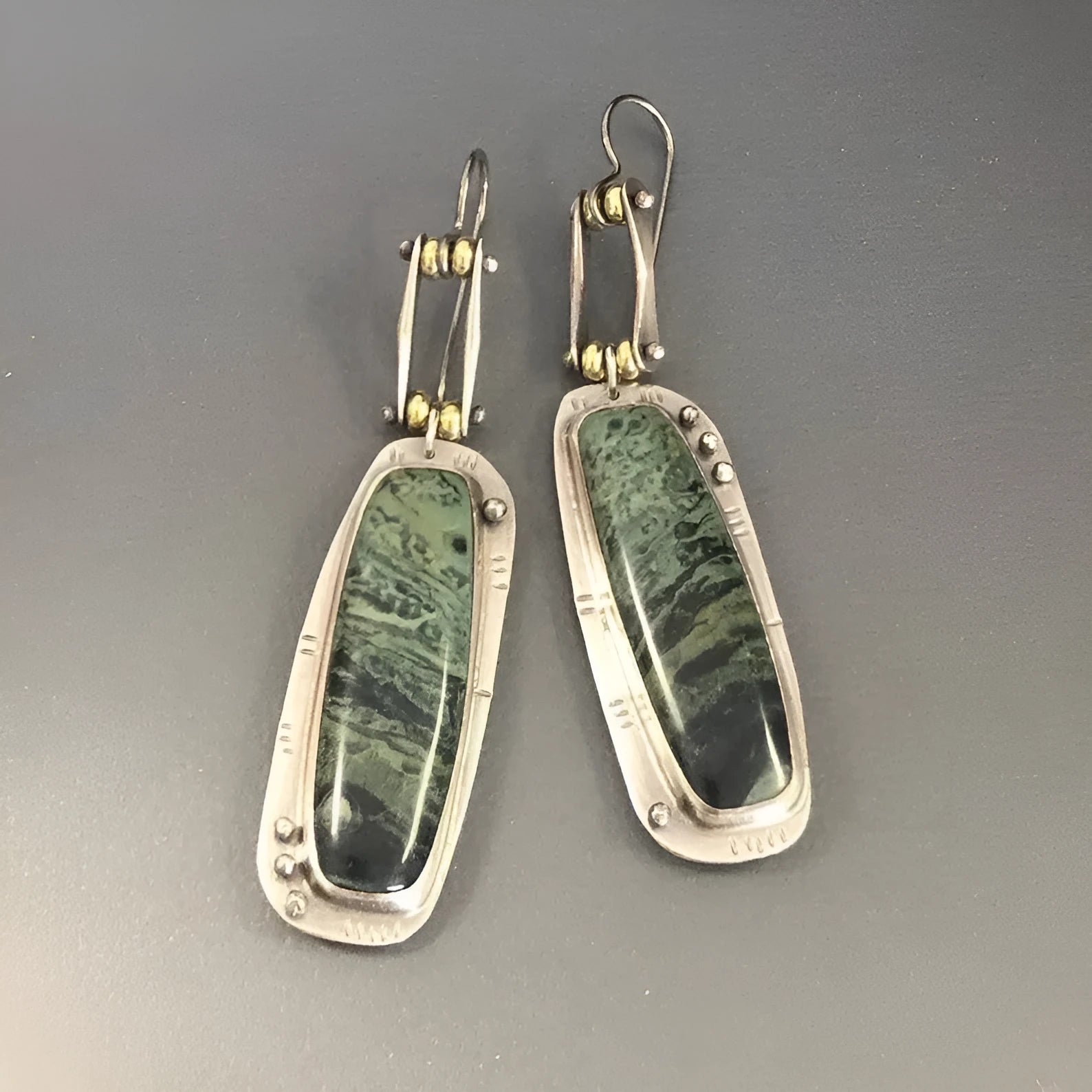 Close-up of women's geometric alloy earrings with a white and grey marble pattern.