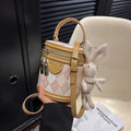 Textured rhombus cylindrical PU bucket bag in beige with white rabbit pendant, 14 cm wide.