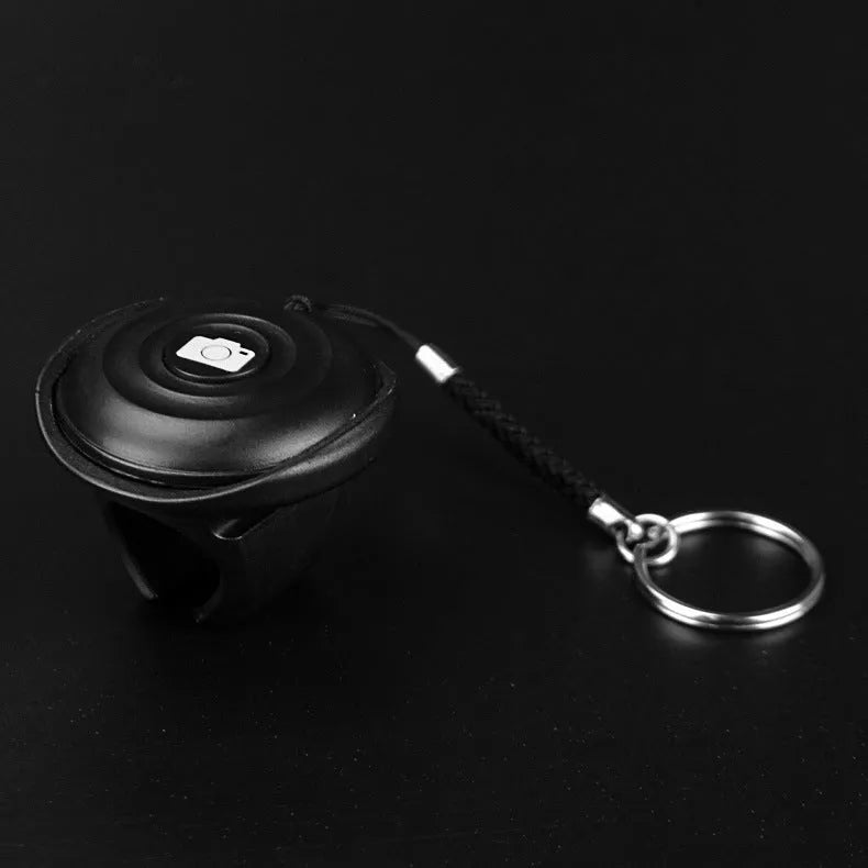 Black Snap Bluetooth remote control for wireless smartphone camera shutter, shown on a white background.