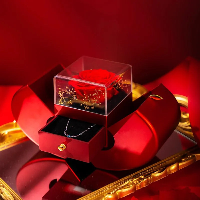 Red apple-shaped jewelry box with eternal soap flower rose and silver necklace inside