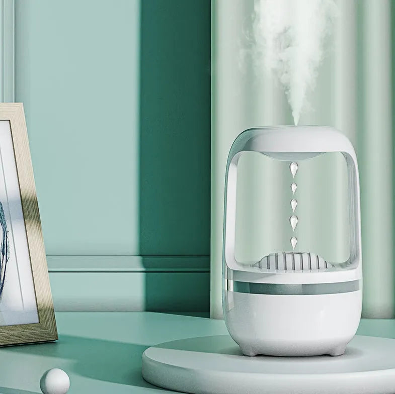 White anti-gravity water droplet humidifier on a table with USB cable, showing mist output