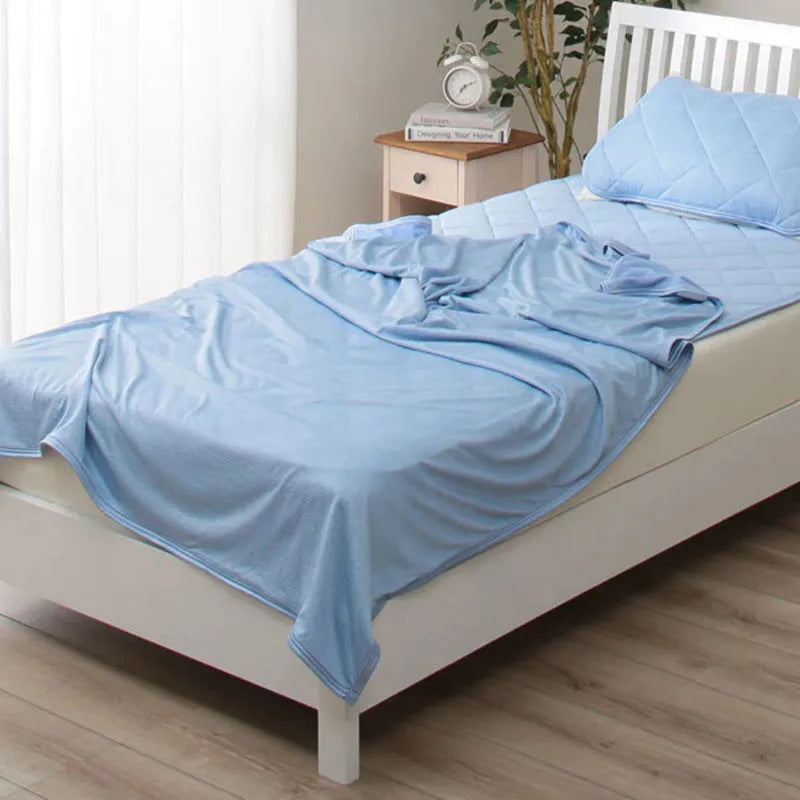 Blue Japanese cooling blanket with Q-Max fibres laid flat on a bed.
