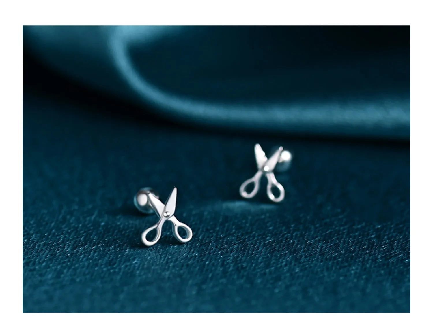 Silver screw-back ear nail with a small scissor charm for cartilage piercing.
