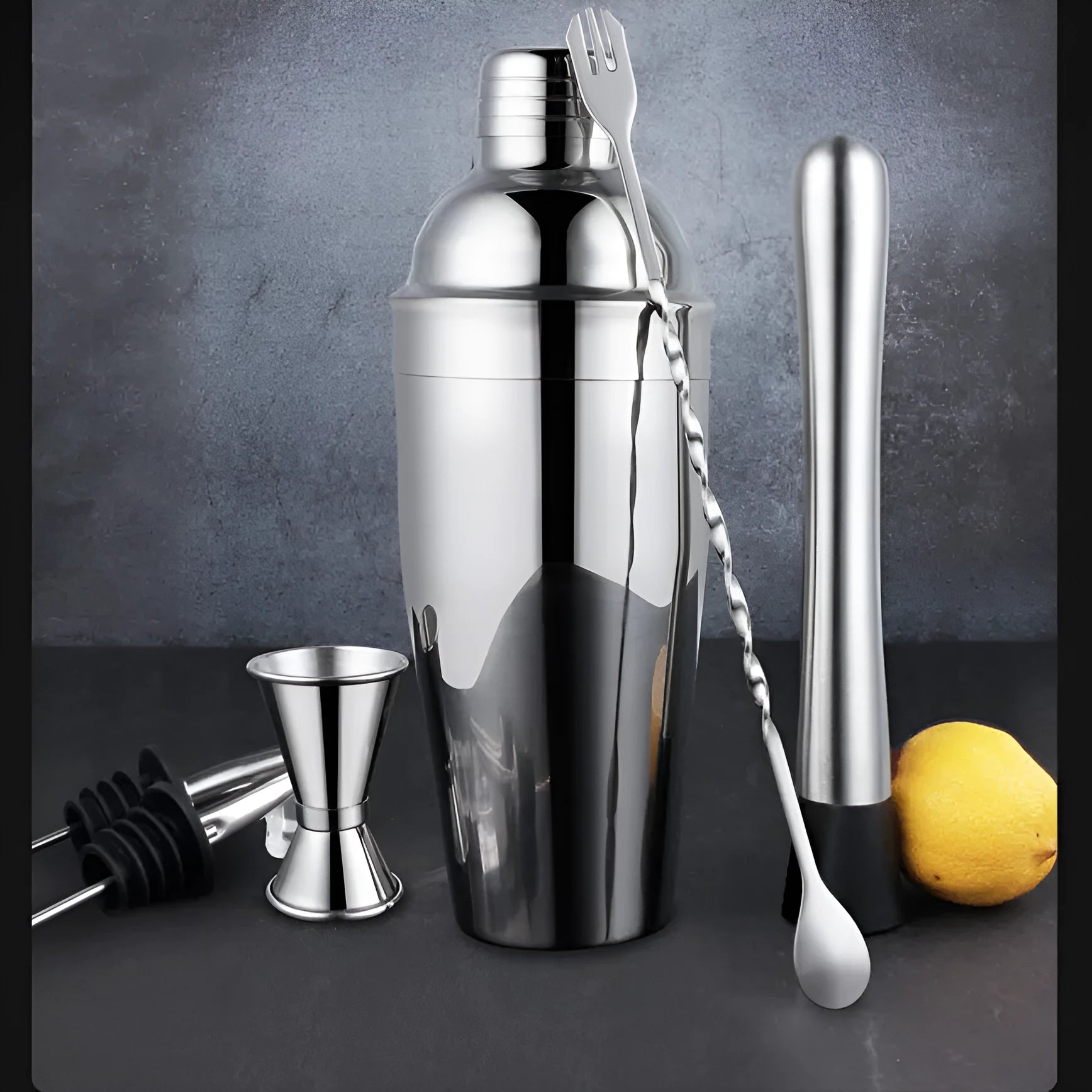 23-piece stainless steel cocktail set with shaker, jigger, strainer, and other bar tools on a wooden surface.