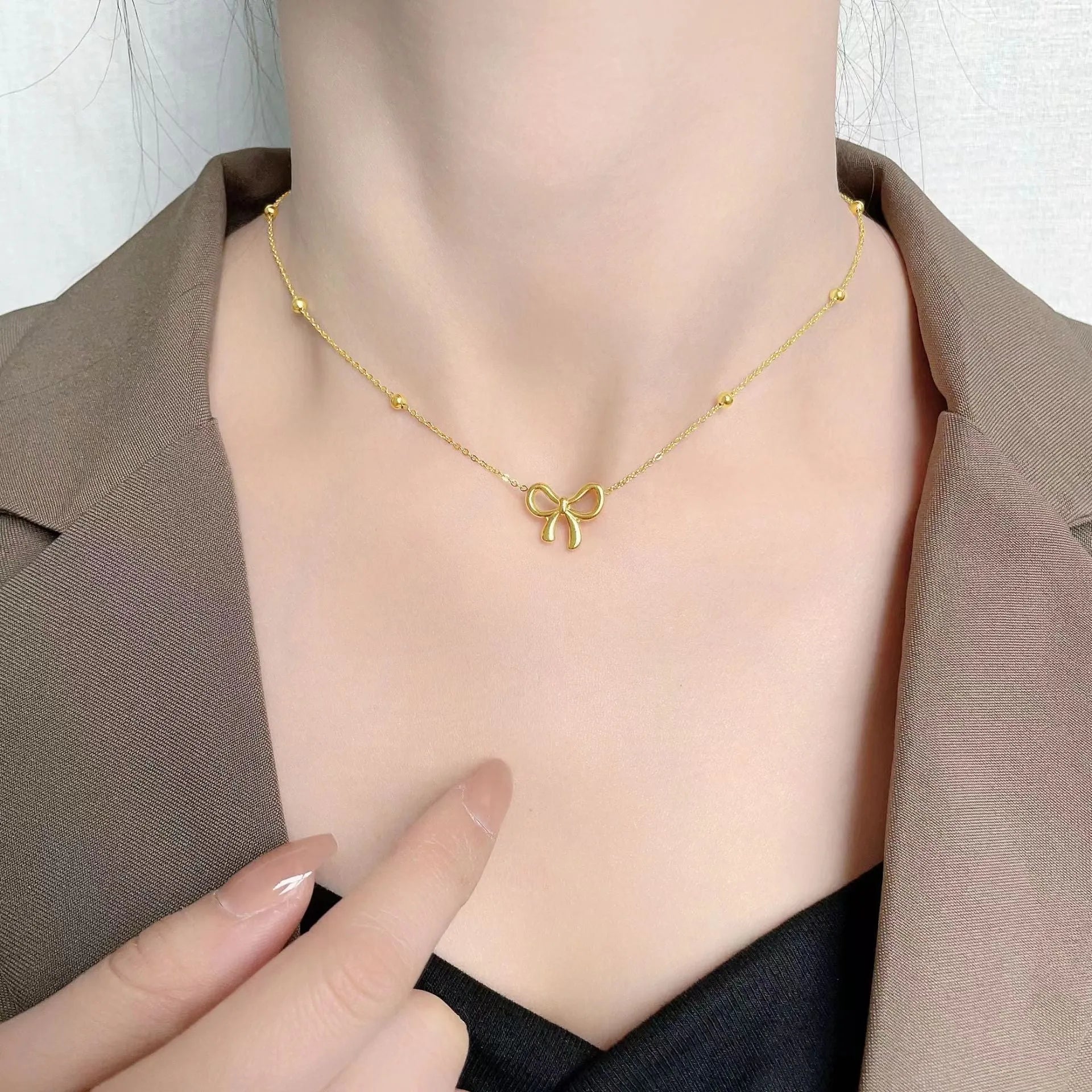 Gold bow necklace with cross chain design showing adjustable length from 41 to 50cm