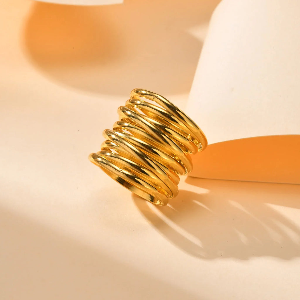 Gold stainless steel multi-loop multi-layer ring on a plain background