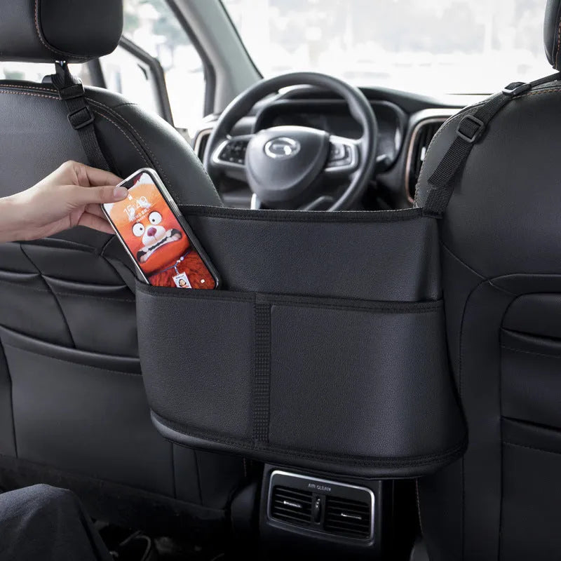 Black leather car seat storage bag with a carbon fibre pattern, shown mounted between car seats.