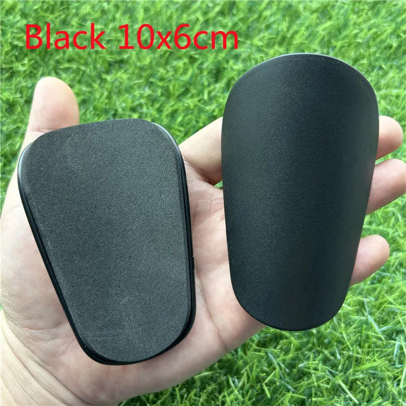Pair of extra small black and white plastic football shin guards, size 8x5cm.