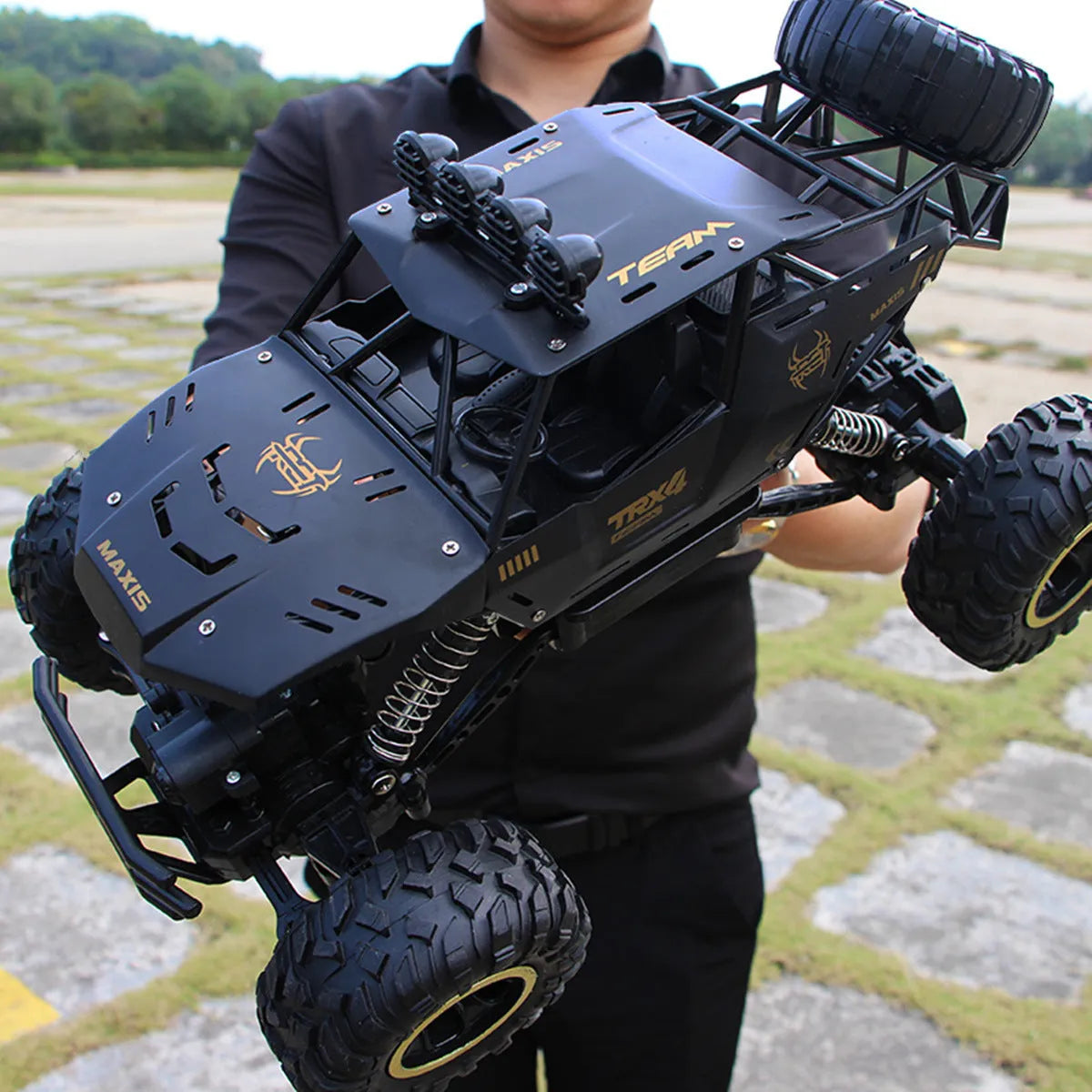 Large black or silver 4WD remote control climbing car on off-road terrain with wireless remote.