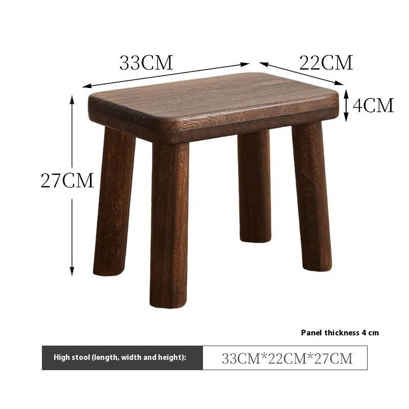 Solid wood distressed finish shoe changing stool with bracket legs in a living room setting.
