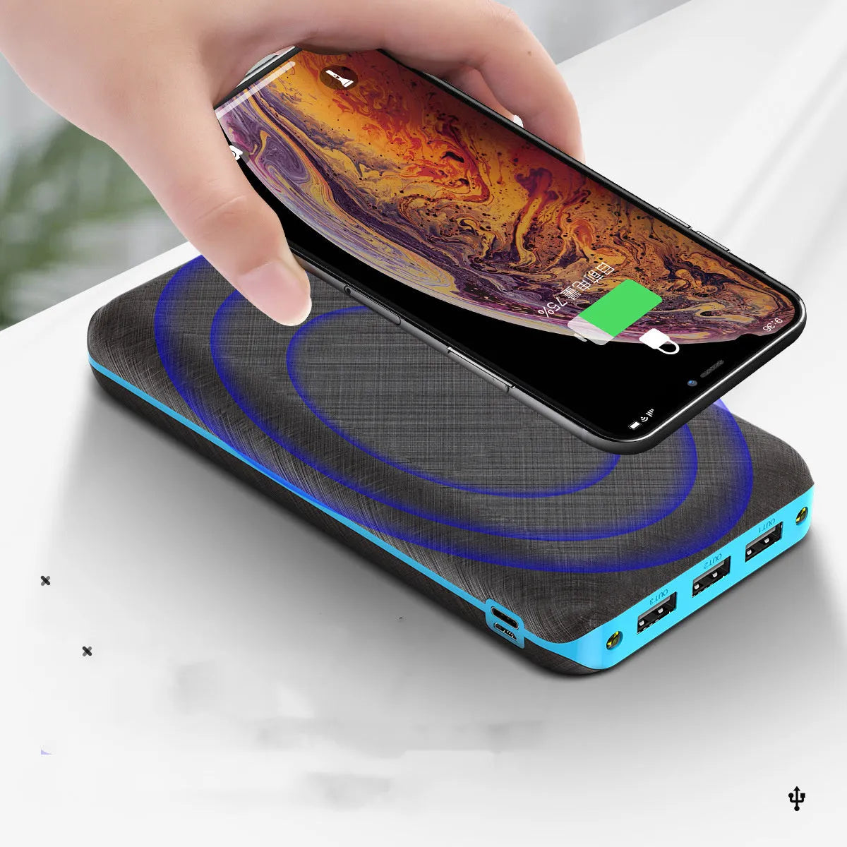 Black portable power bank with wireless charging pad on top, three USB ports, and an LED flashlight.