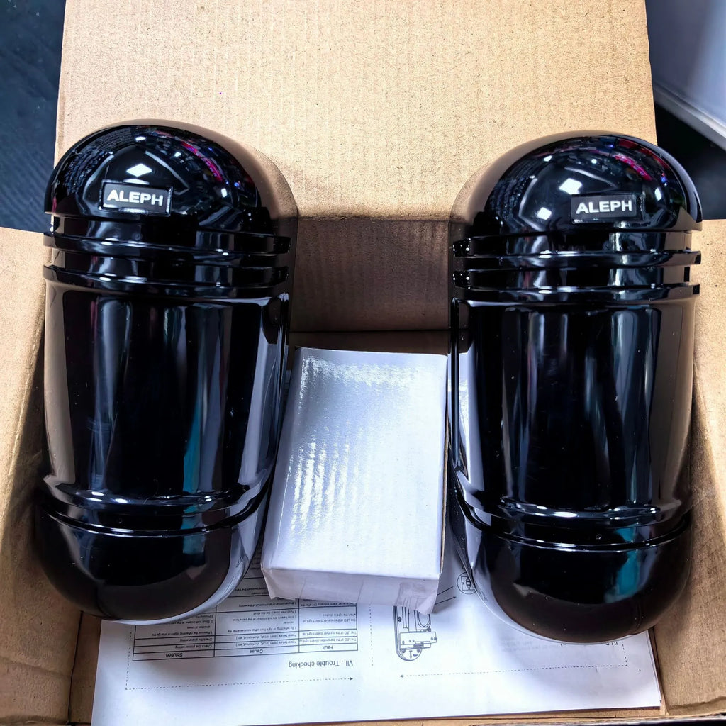 A pair of black wall-mounted infrared security detectors with wired terminals.