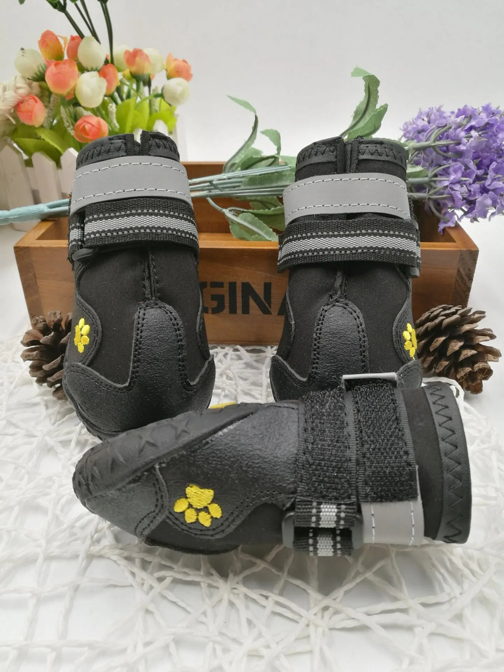 Black dog shoes with waterproof PVC sole and adjustable fuzzy belt on a dog's paw