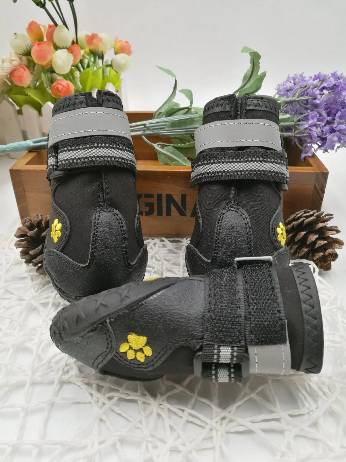 Black dog shoes with waterproof PVC sole and adjustable fuzzy belt on a dog's paw