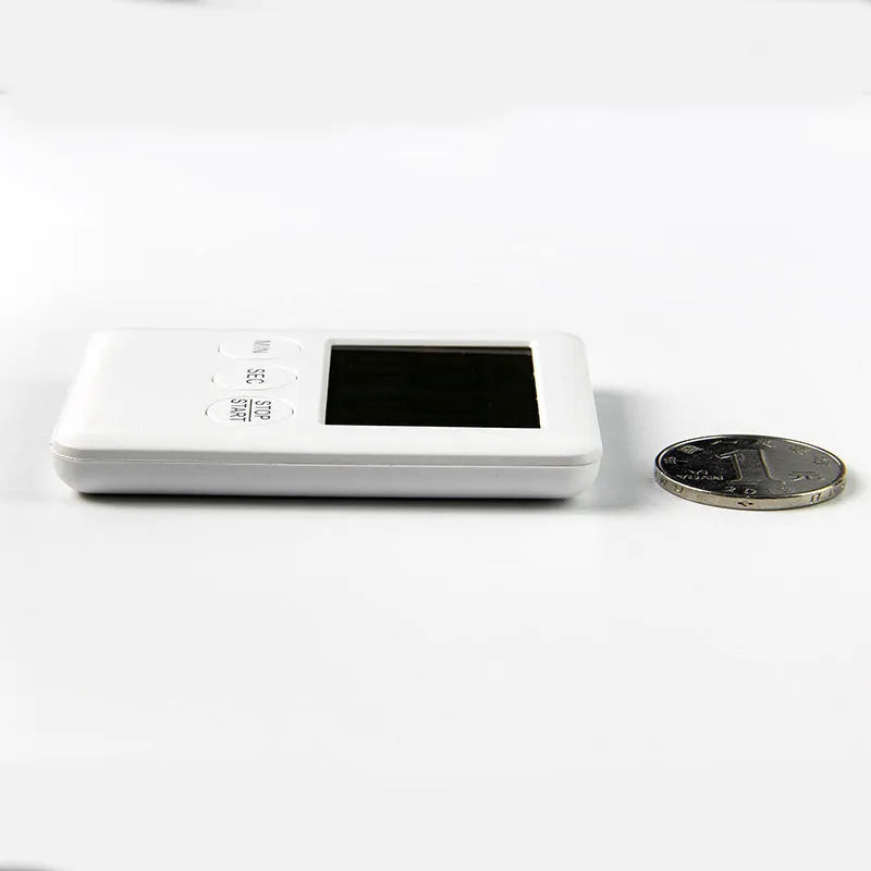 Black and white digital kitchen timer with LCD screen and magnetic back on a fridge