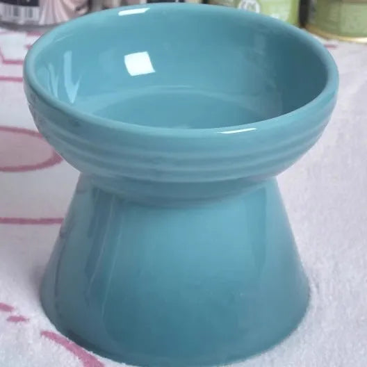 A white ceramic pet bowl with a high foot and raised neck protector to prevent tipping.