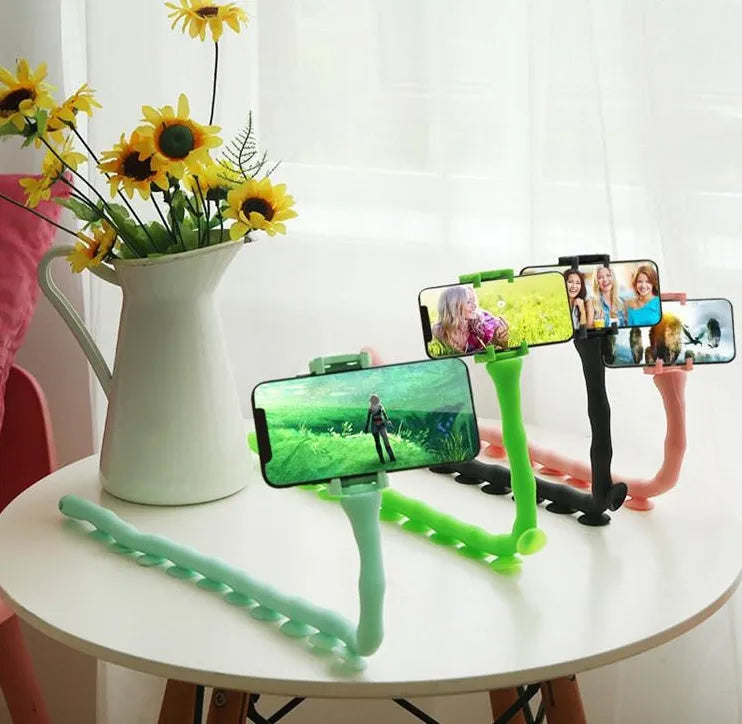Flexible black rubber phone holder with suction cup extended, showing 360° rotation joint next to a mobile phone.