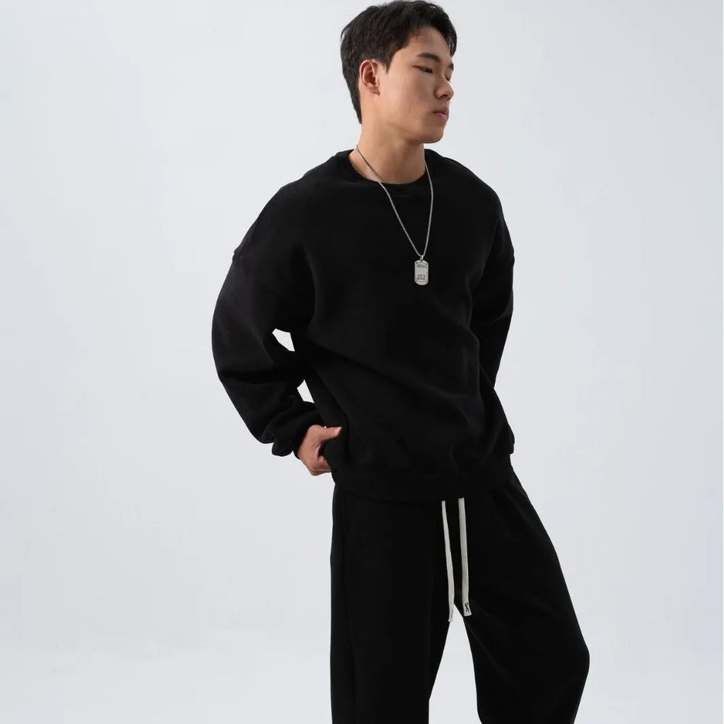 Men's black polar fleece sports suit with loose crew neck jacket and padded trousers on a hanger.