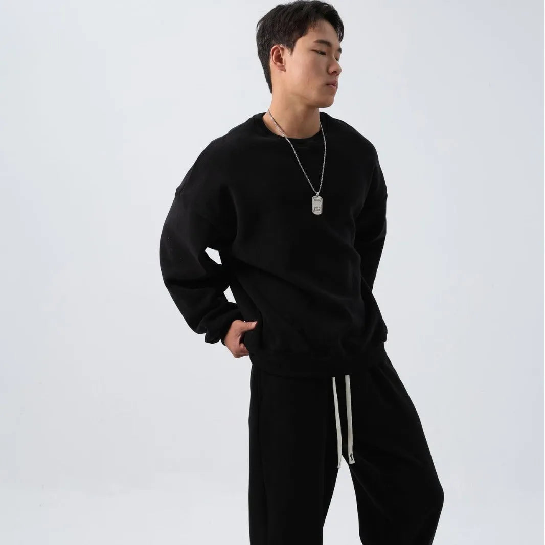 Men's black polar fleece sports suit with loose crew neck jacket and padded trousers on a hanger.