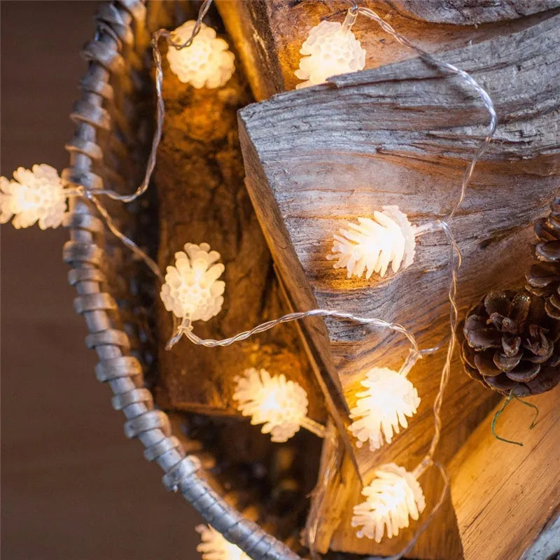Warm white plastic pine cone LED light string powered by batteries on a dark background.