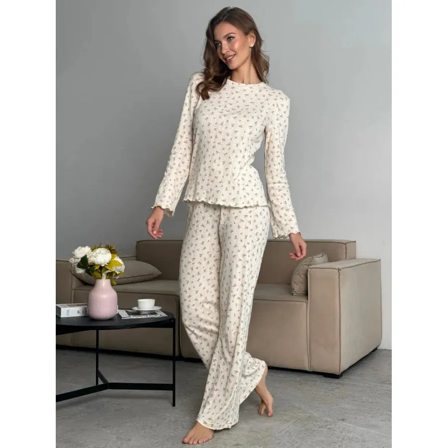 White women's floral print two-piece suit with bell sleeve top and wide leg pants on a hanger.