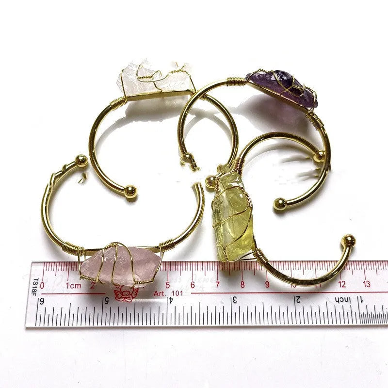 Natural rough crystal bracelet with geometric gold metal winding on a wrist.