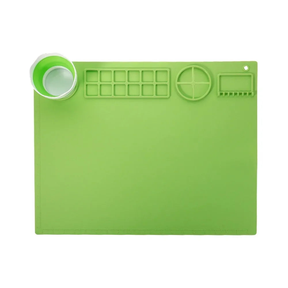 Light blue silicone painting mat with an integrated bowl on one side, positioned on a wooden table.