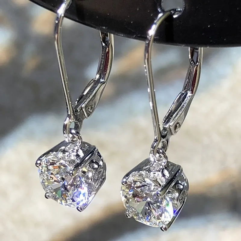 Silver-toned cubic zirconia stud earrings with 4mm round stone in claw setting on white background