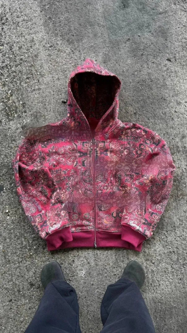 A man's loose-fitting red hooded zip coat with long sleeves, shown on a hanger.