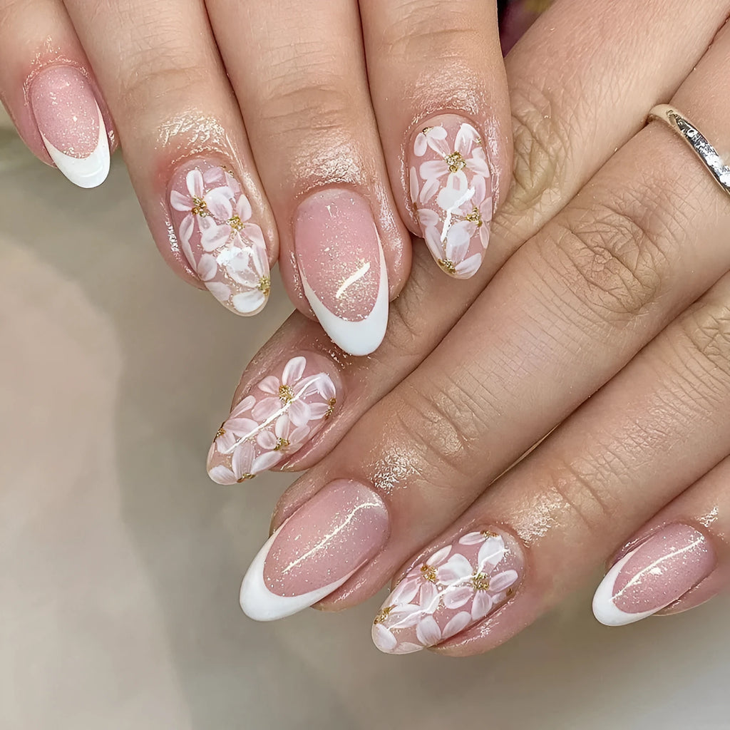Short almond shaped faux nails with French manicure style and glittery pink flower design.