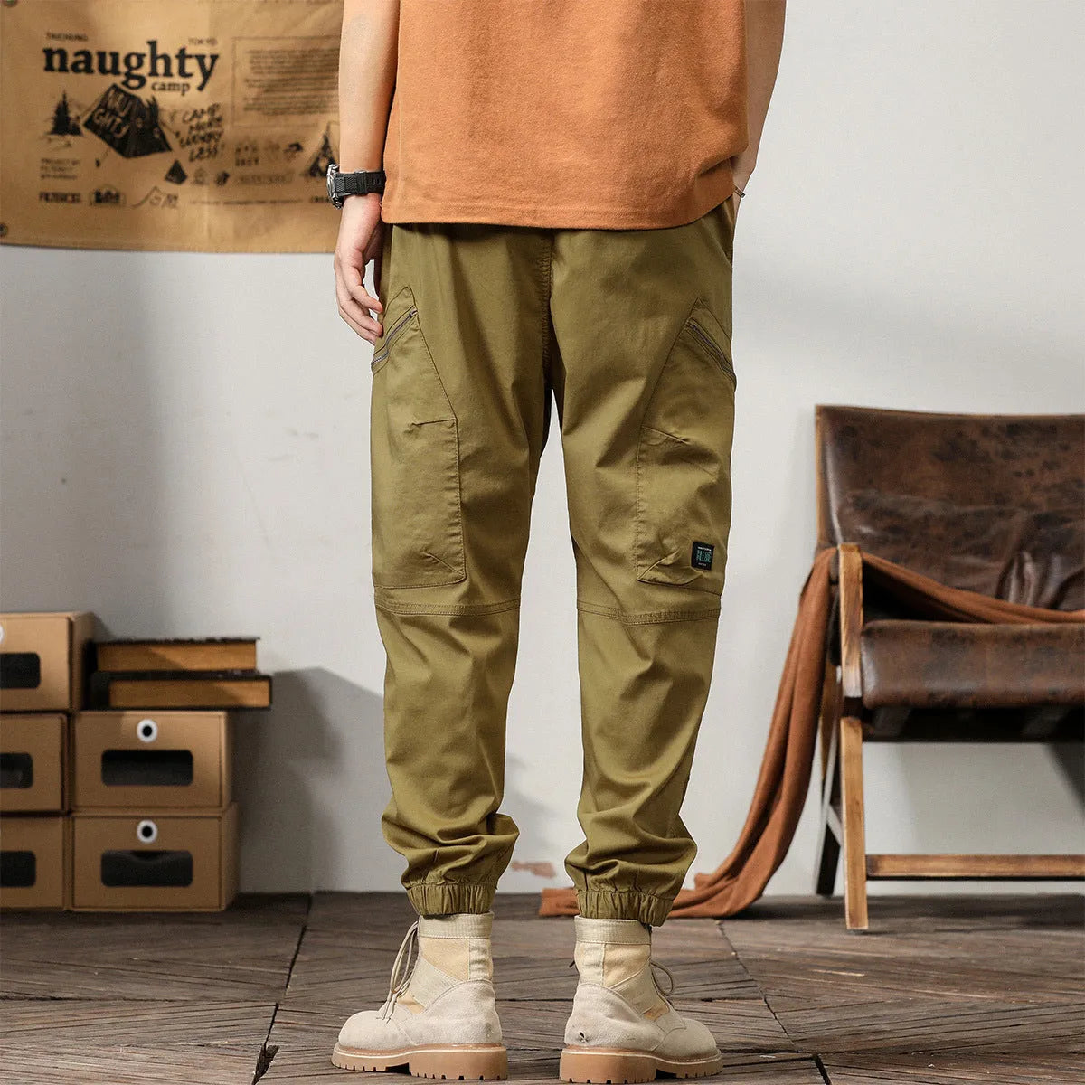 Men's khaki cotton tapered harem pants with ankle bands and a zip fly, laid flat.