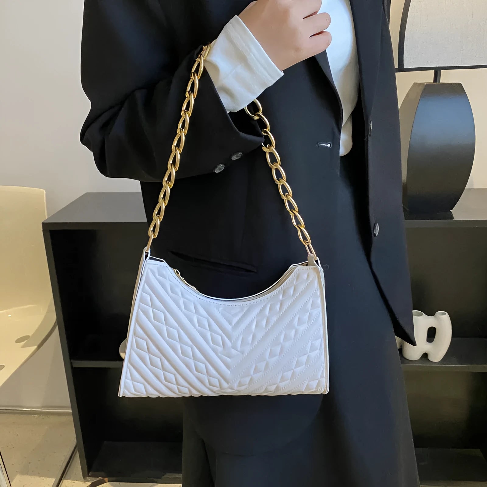 Vertical square brown PU shoulder bag with chain strap and soft handle on a table