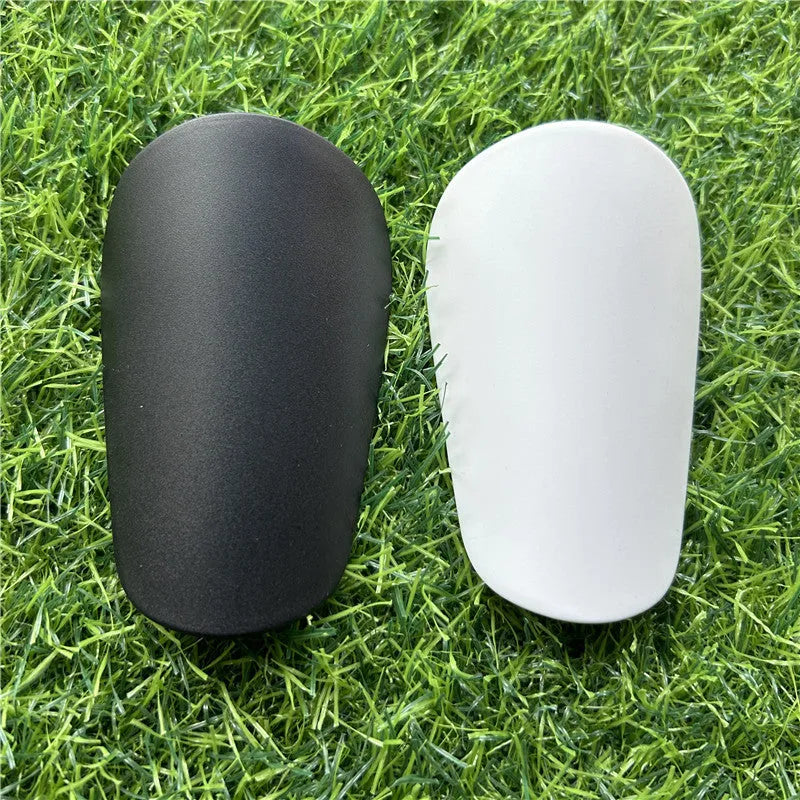 Pair of extra small black and white plastic football shin guards, size 8x5cm.