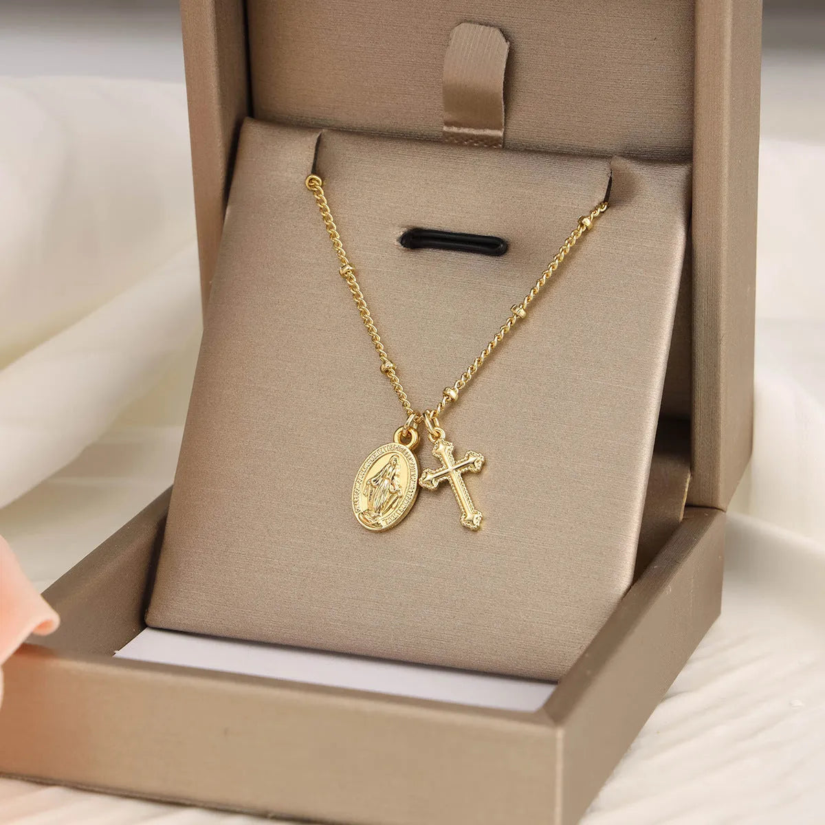 Gold Virgin Mary cross necklace with simple geometric pendant on a chain.