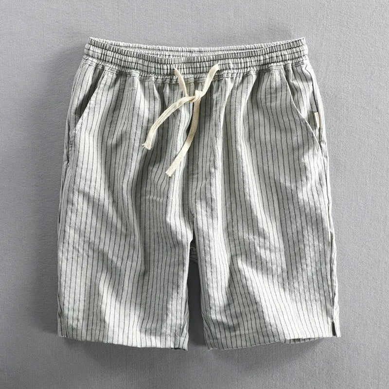 Man wearing striped light blue cotton casual shorts with a mid waist and loose straight fit.