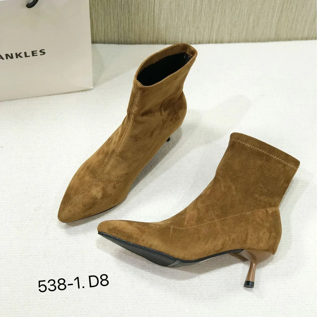 Women's black pointed toe ankle boots with a stiletto heel and mid-calf sock length.