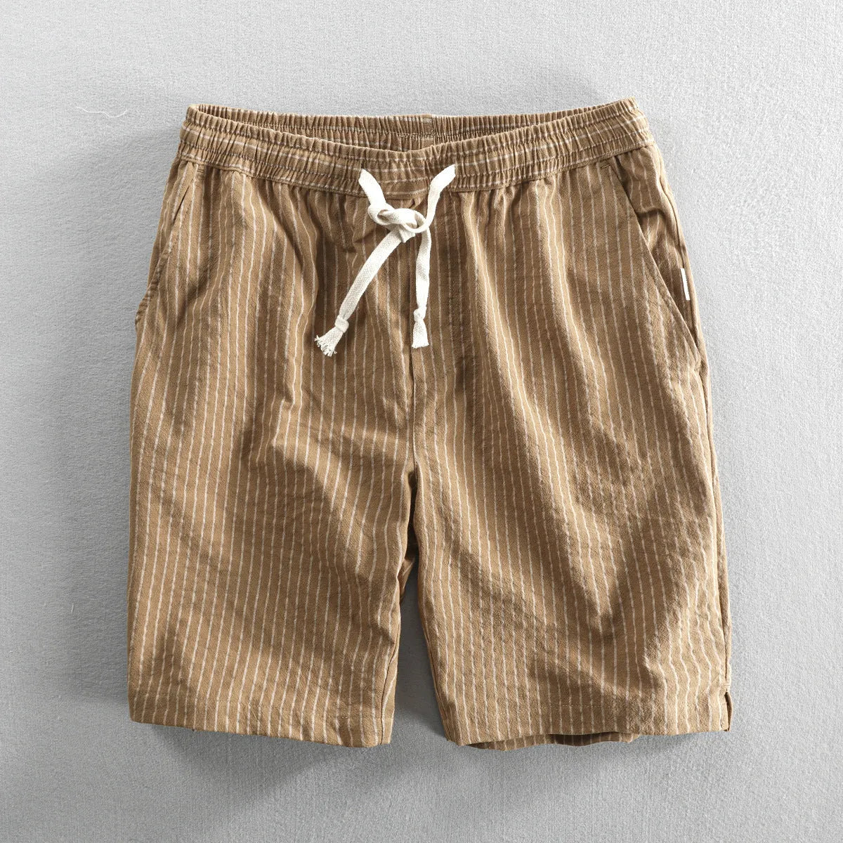 Man wearing striped light blue cotton casual shorts with a mid waist and loose straight fit.