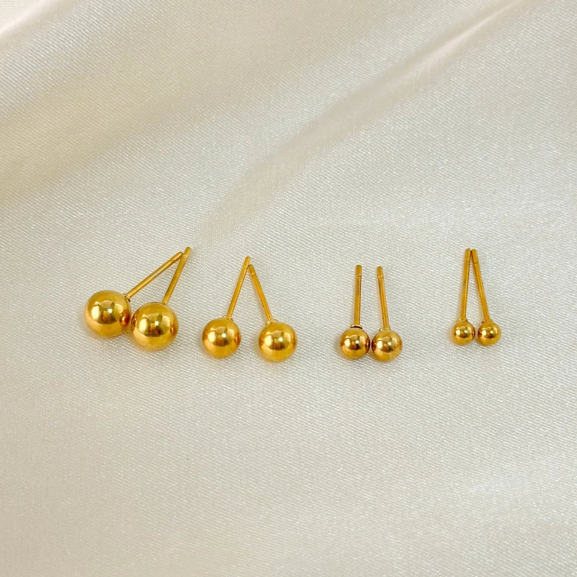 Stainless steel round ball stud earrings on a white background, showing gold and silver plated options.